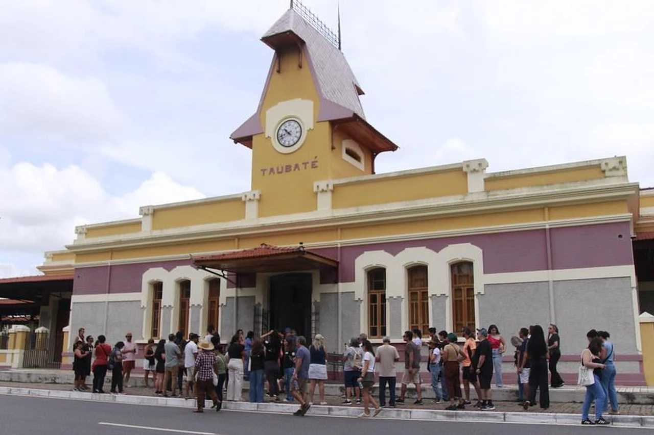 Fachada da estação ferroviária com o nome Taubaté e pessoas diante do edifício.