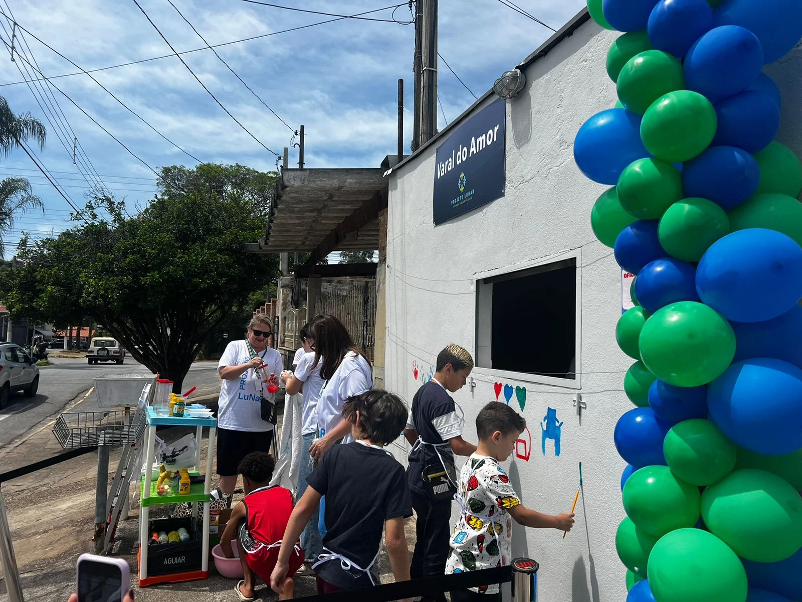 Crianças pintam a parede junto a voluntários do Projeto Lunar.