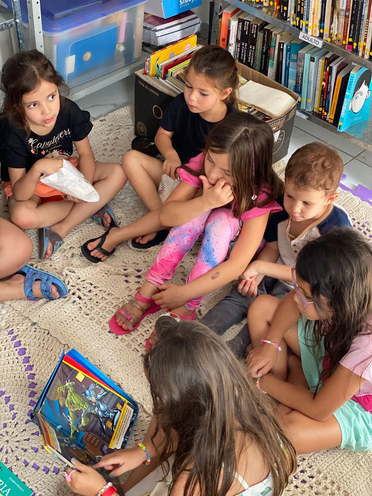 Crianças e adultos participam de atividade com livros.