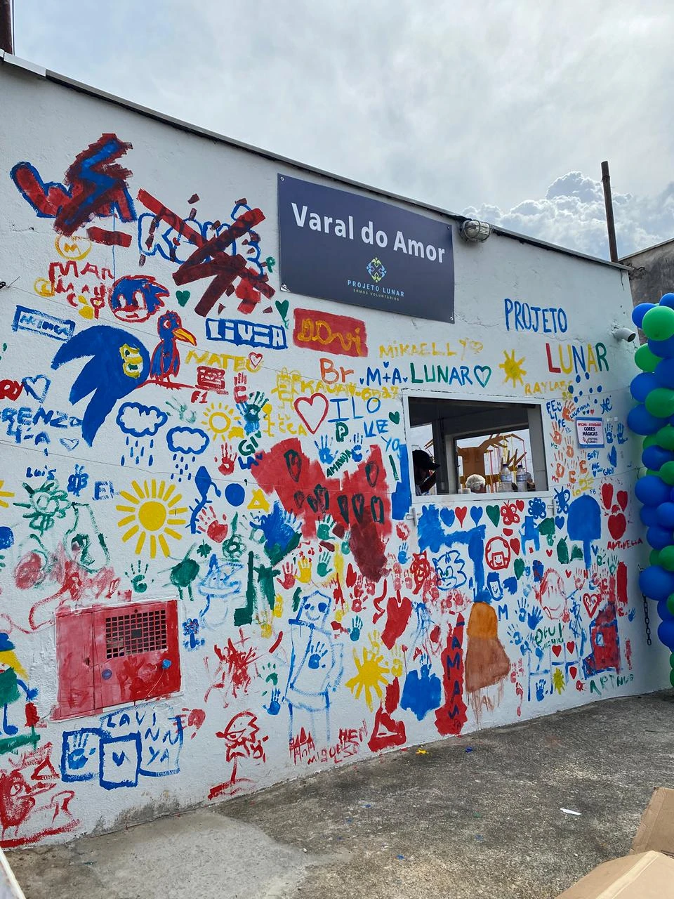 Parede decorada com desenhos e marcas de mãos coloridas.