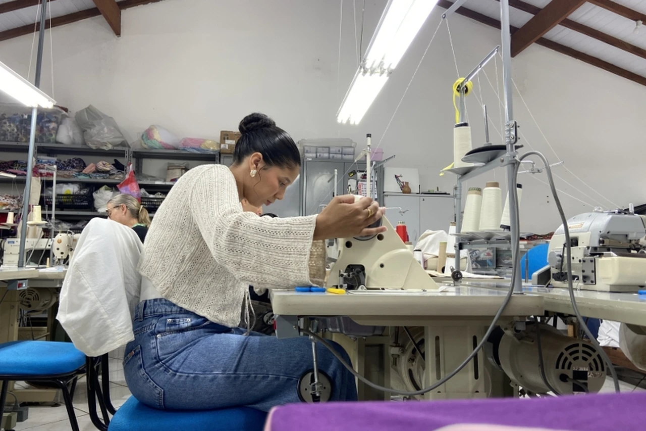 Mulher trabalhando em máquina de costura em um ambiente de formação profissional.