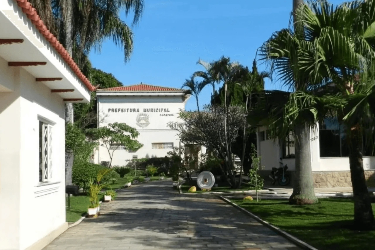 Entrada da Prefeitura Municipal de Caçapava, com jardim e palmeiras.
