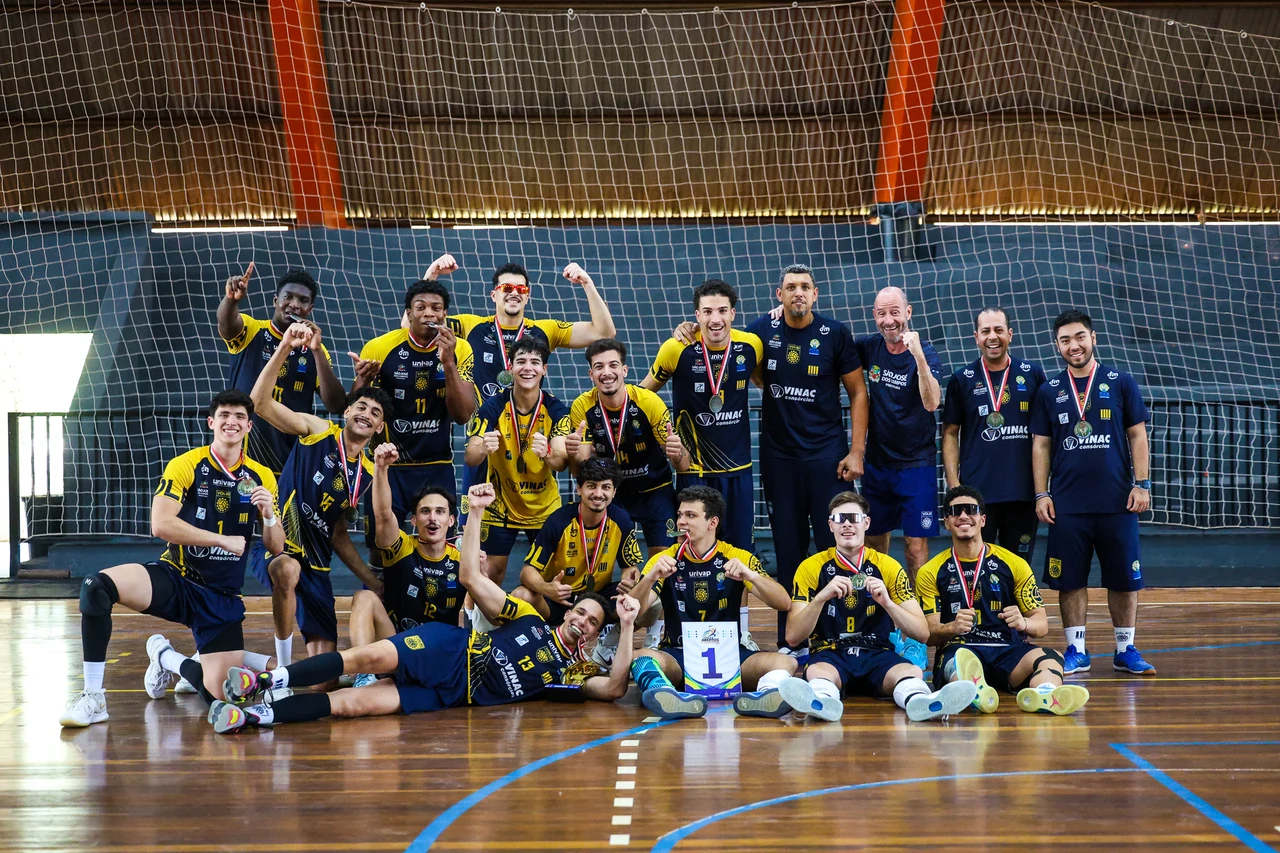 Atletas e integrantes da equipe de São José dos Campos posam com medalhas em uma quadra.